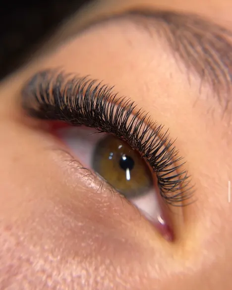 Ojo marrón mirando hacia arriba con extensiones de pestañas efecto aura, con textura