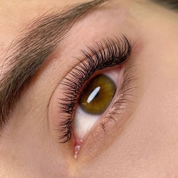 Primer plano de un ojo marrón con extensiones de pestañas efecto semi tupida