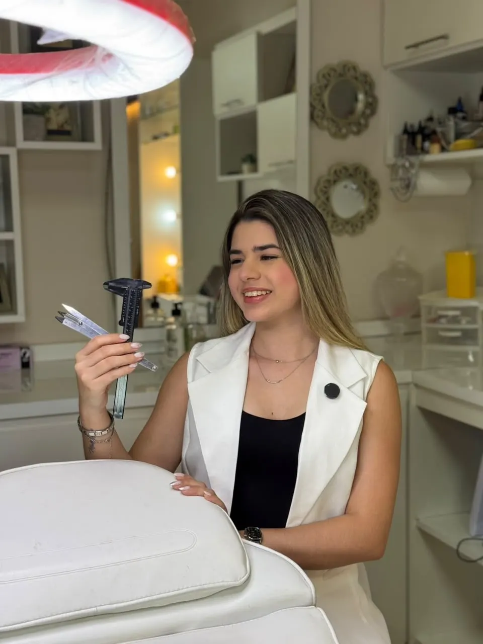 Sol Cristaldo sonriendo en su estudio, junto a la camilla, con herramientas de medición de cejas en la mano